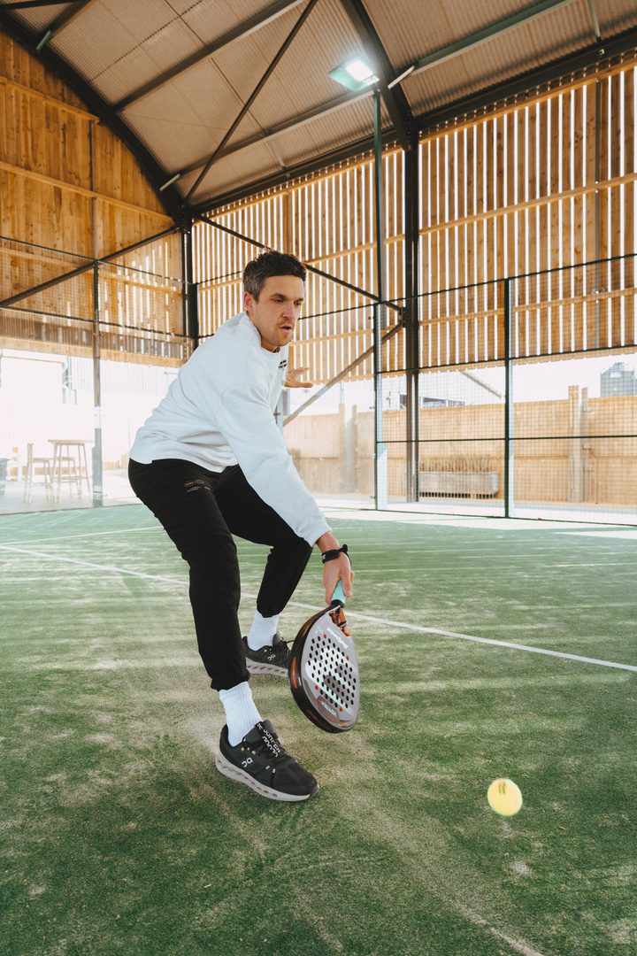 Player hitting a low volley on an indoor court