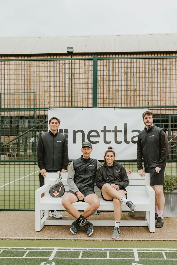 Nettla team on a courtside bench in front of the Nettla banner